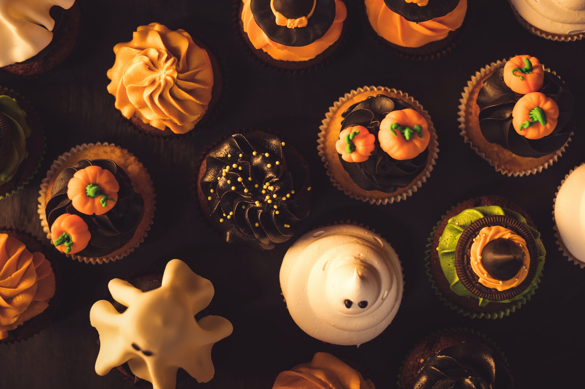 top view of traditional tasty halloween cupcakes on black